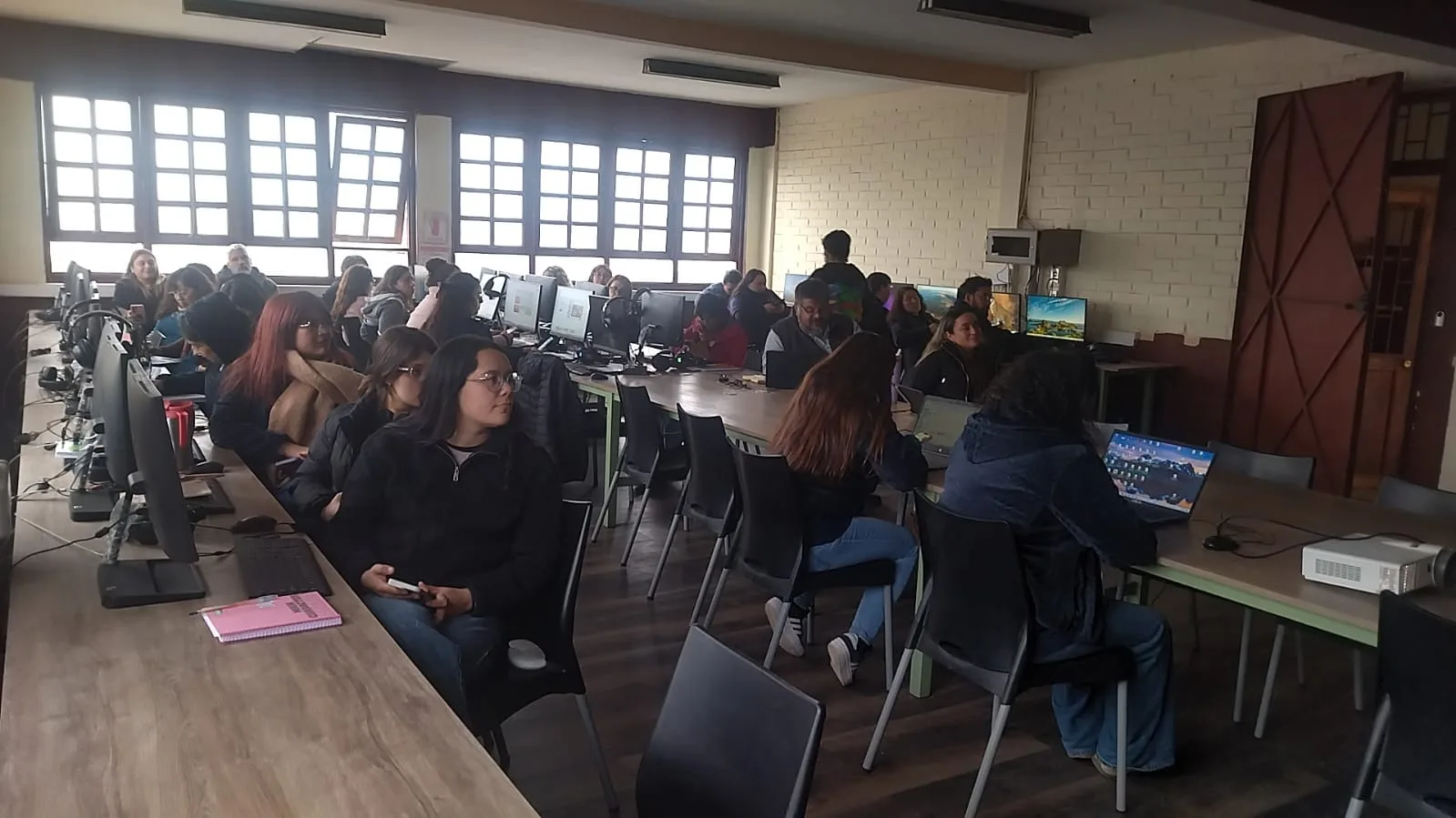 Participantes trabajan en grupos con computadores durante la capacitación